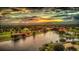 An aerial view of a waterfront community with residences lining the shore of a dark, winding lake at sunset at 17304 Vagabond Cir, Punta Gorda, FL 33955