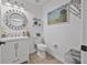 Clean and bright bathroom featuring a modern vanity, round mirror, updated fixtures, and beachy artwork at 17304 Vagabond Cir, Punta Gorda, FL 33955