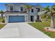Beautiful two story home featuring a light blue garage door, stucco exterior and mature tropical landscaping at 17304 Vagabond Cir, Punta Gorda, FL 33955