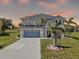 Beautiful two story home featuring a light blue garage door, stucco exterior and mature tropical landscaping at 17304 Vagabond Cir, Punta Gorda, FL 33955