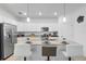 Modern white kitchen with stainless steel appliances, granite counters, and breakfast bar seating at 17620 Winding Wood Ln, Punta Gorda, FL 33982