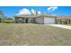 Exterior view of a single-story house with a lush green lawn and an attached two car garage at 18503 Ellen Ave, Port Charlotte, FL 33948
