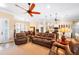 Spacious living room with open layout to the kitchen, featuring a ceiling fan and comfortable leather furniture at 19246 Moore Haven Ct, Port Charlotte, FL 33948