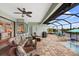 Relaxing screened lanai with stylish wicker furniture, ceiling fan, and a view of the pool and waterfront at 19246 Moore Haven Ct, Port Charlotte, FL 33948