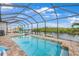 Screened-in pool with a view of the water, lounge chairs, and a clear blue sky at 19246 Moore Haven Ct, Port Charlotte, FL 33948