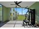 Screened balcony featuring workout equipment and a ceiling fan with views of the lawn and nearby buildings at 2160 Heron Lake Dr # 201, Punta Gorda, FL 33983