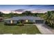 Charming single-story home at dusk, featuring a lush lawn, colorful shrubs, and inviting outdoor lighting at 2193 Beacon Dr, Port Charlotte, FL 33952
