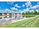 Beautiful lake view from back of property surrounded by vibrant green grass and gorgeous blue sky at 25100 Sandhill Blvd # F-203, Punta Gorda, FL 33983