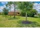 Lush backyard with green lawn, mature trees, and view of the home's exterior at 253 Marcheno Way, Nokomis, FL 34275
