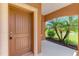 Charming front door with a secure keyless entry and arched detailing with a view of palm trees from the covered porch at 253 Marcheno Way, Nokomis, FL 34275