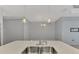 Quartz countertop island has stainless steel sink, modern faucet, and pendant lights at 253 Marcheno Way, Nokomis, FL 34275