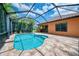 Sparkling pool in screened lanai with patio and lush tropical foliage in the background at 253 Marcheno Way, Nokomis, FL 34275