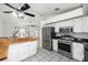 Open-concept kitchen with white cabinets, stainless steel appliances, and a breakfast bar overlooking the living area at 25449 Doredo Dr, Punta Gorda, FL 33955
