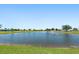 Scenic pond with a fountain surrounded by green grass and neighborhood homes under a clear blue sky at 25449 Doredo Dr, Punta Gorda, FL 33955