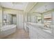 Bathroom featuring dual sinks, a vanity area, and a separate bathtub and glass block shower at 2719 Mayaguana Ct, Punta Gorda, FL 33950