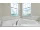 Bright bathroom featuring a pristine white bathtub with chrome fixtures and two windows at 2913 Royal Palm Dr, North Port, FL 34288