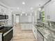 Spacious, updated kitchen with granite countertops, white cabinets, stainless steel appliances, and modern lighting fixtures at 3342 Avanti Cir, North Port, FL 34287