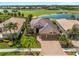 Stunning aerial view of a tile roofed home with a three car garage, lush landscaping, and water views at 5461 White Ibis Dr, North Port, FL 34287
