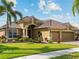 Beautiful home featuring a well-manicured lawn, mature landscaping, and a three-car garage at 5461 White Ibis Dr, North Port, FL 34287