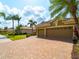 Three-car garage and driveway with palm trees, landscaping, and a sunny sky at 5461 White Ibis Dr, North Port, FL 34287
