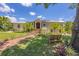 Charming home with a lush front yard, brick walkway, mature trees and manicured landscaping at 6242 Tropicaire Blvd, North Port, FL 34291