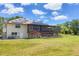 Home's rear exterior featuring a spacious yard, solar panels, screened porch, and deck at 6242 Tropicaire Blvd, North Port, FL 34291