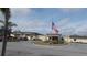 Exterior of a well-maintained building displaying the American flag, with landscaping and parking area in view at 6832 Holo Ct, North Port, FL 34287