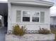 Cozy mobile home exterior features a large window with light green shutters and a planter in front at 6832 Holo Ct, North Port, FL 34287