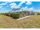 Backyard featuring a screened lanai, lush landscaping, and a built-in grill, perfect for outdoor entertainment at 732 Santa Margerita Ln, Punta Gorda, FL 33950