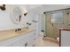 Bathroom with a vanity, round mirror, a glass shower, and neutral tiling at 732 Santa Margerita Ln, Punta Gorda, FL 33950