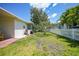View of the backyard showcasing the well-maintained lawn, mature trees, and white picket fence at 809 Kings Ct, Punta Gorda, FL 33950