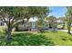 Charming home featuring a lush green lawn, mature trees, and a quaint entrance with a light blue door at 809 Kings Ct, Punta Gorda, FL 33950