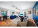 Bright living room with wood-look floors, comfortable sofas, and a desk with computer near large windows at 809 Kings Ct, Punta Gorda, FL 33950