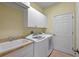 Well-lit laundry room with a washer, dryer, sink, and ample cabinet space at 13297 Flaherty Ave, Port Charlotte, FL 33981