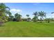 Expansive green lawn in backyard featuring tropical landscaping and a screened-in lanai at 16232 Quesa Dr, Punta Gorda, FL 33955