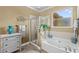 Well-lit bathroom with a large tub, glass shower, tile surround, and charming coastal accents at 16232 Quesa Dr, Punta Gorda, FL 33955
