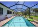 A screened in pool with bright water, and a large green yard with trees in the background at 16615 Acapulco Rd, Punta Gorda, FL 33955