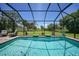 A screened in pool with bright water, and a large green yard with trees in the background at 16615 Acapulco Rd, Punta Gorda, FL 33955