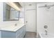 Bathroom with white-tiled shower, bathtub, blue vanity and elegant mirror at 18111 Lake Worth Blvd, Port Charlotte, FL 33948
