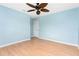Light blue bedroom with wood floor, ceiling fan, and door at 18111 Lake Worth Blvd, Port Charlotte, FL 33948