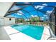 Enjoy swimming in this screened-in pool with a blue sky above, surrounded by lush landscaping at 18111 Lake Worth Blvd, Port Charlotte, FL 33948