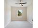 Bright bedroom with ceiling fan, tile flooring, and a view to the greenery outside at 19092 Woodbine Ave, Port Charlotte, FL 33954