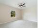 Bedroom with neutral walls, a ceiling fan, tile floors, and a window with backyard views at 19092 Woodbine Ave, Port Charlotte, FL 33954