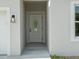 Close-up of the front door with an oval glass insert and modern light fixture at 19092 Woodbine Ave, Port Charlotte, FL 33954
