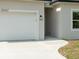 Attached two-car garage with white door and modern exterior lighting fixture at 19092 Woodbine Ave, Port Charlotte, FL 33954