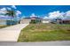 A single-Gathering home featuring a spacious driveway and well-manicured lawn, complete with solar panels at 211 E Tarpon Nw Blvd, Port Charlotte, FL 33952