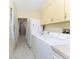 Convenient laundry room includes a washer, dryer, additional fridge, built-in cabinets, and access to hall at 233 Beeney Se Rd, Port Charlotte, FL 33952
