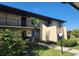 Exterior of condo complex featuring mature palm trees, a black railing and beige stucco at 4056 Oakview Dr # E10, Port Charlotte, FL 33980