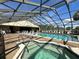 Enclosed community pool featuring hot tub, seating and blue skies through a screened enclosure at 4056 Oakview Dr # E10, Port Charlotte, FL 33980