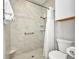 Walk-in shower with grey tiling and grab bar in a well-maintained bathroom with toilet and a towel at 4231 Hollis Ave, Port Charlotte, FL 33953